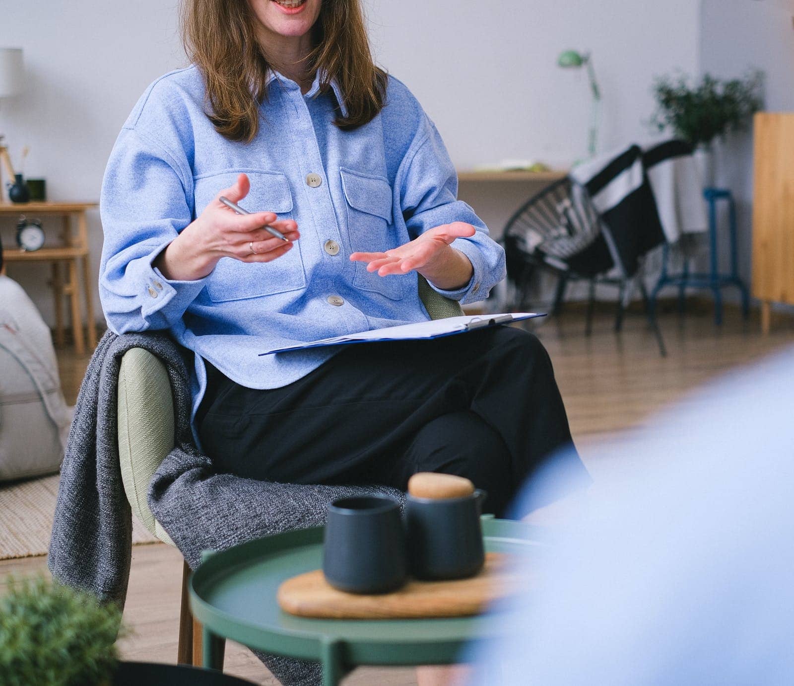 Woman in a blue shirt gesturing while talking in a counseling session